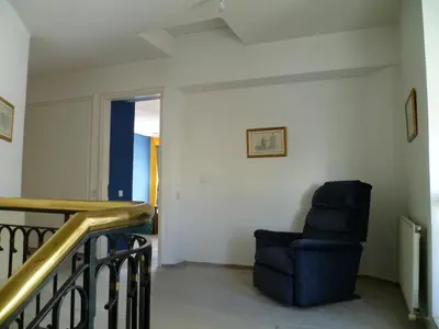 a living room with a blue chair and a staircase at Private deluxe room with balcony at Datacom building in Nicosia