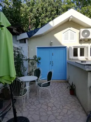 a patio with a table and chairs and a blue garage at Swallows Nest in Larnaka