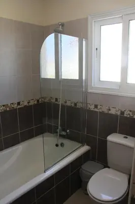 a bathroom with a tub and a toilet and a window at Maricosta Villas in Protaras