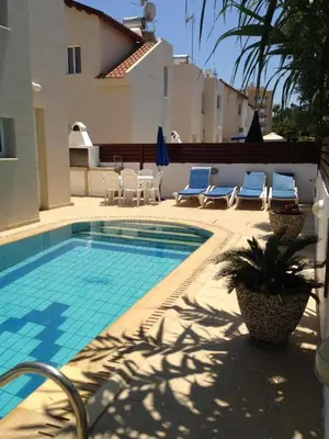 a swimming pool with blue chairs and a house at Maricosta Villas in Protaras