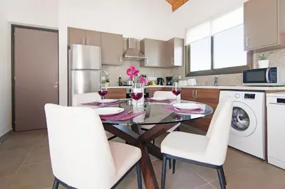 a kitchen with a dining room table and white chairs at Villa Marion in Ayia Napa