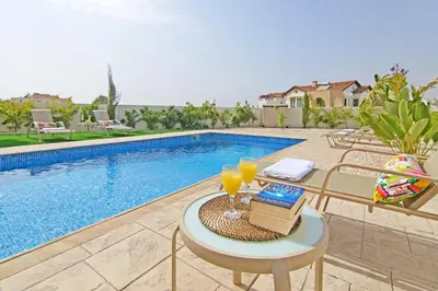 a table with two glasses of orange juice next to a pool at Villa Marion in Ayia Napa