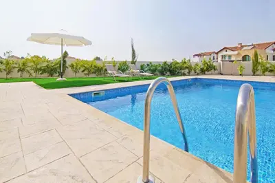 a swimming pool with an umbrella next to a house at Villa Marion in Ayia Napa