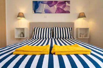 a bed with two yellow pillows on top of it at Blue Dawn Center Flat in Larnaka