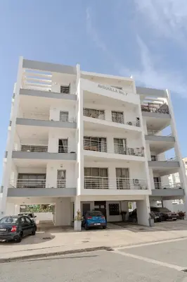 a white building with cars parked in front of it at Violet Dusk City Center Flat in Larnaka
