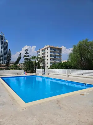 a blue swimming pool with a building in the background at Beachfront Amazing New Apartment in Limassol