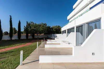 a white building with stairs and trees in the background at Adelais Bay Hotel in Protaras