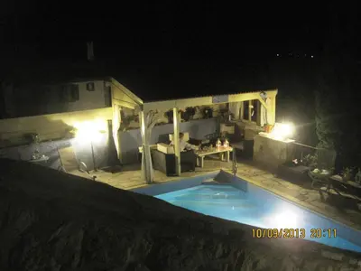 a swimming pool at night with a table and a couch at Oinochori in Vouni