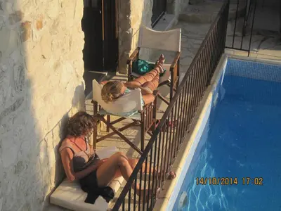 two women laying in chairs next to a swimming pool at Oinochori in Vouni