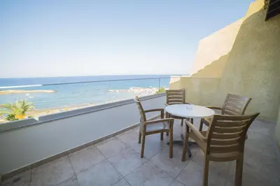 a table and chairs on a balcony with a view of the ocean at MyroAndrou Beach Hotel Apartments in Protaras
