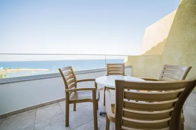 a table and chairs on a balcony with a view of the ocean at MyroAndrou Beach Hotel Apartments in Protaras
