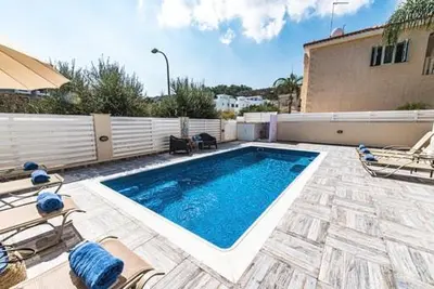 a swimming pool in a yard with chairs and a building at Timotheos Villa in Protaras