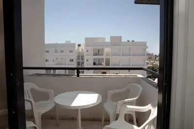 a table and chairs on a balcony with a window at Olive Island in Larnaka