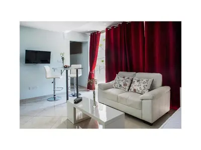 a living room with a white couch and red curtains at Mesogios House Suites in Larnaka