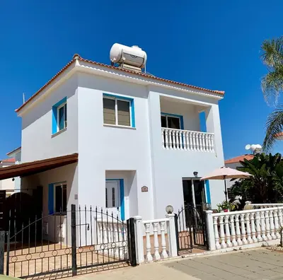 a white house with a fence and a palm tree at Villa Emiliana in Paralimni
