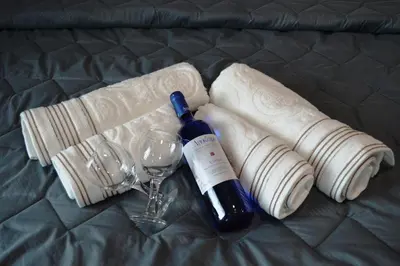 a bottle of wine and a glass on a bed at Millie's Apartments in Ayia Napa