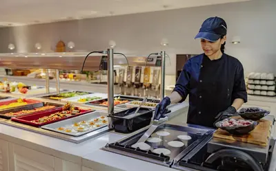 a woman preparing food in a restaurant kitchen at Tasia Maris Oasis in Ayia Napa