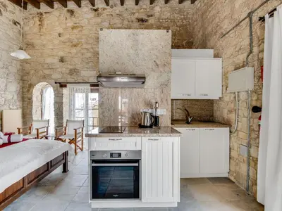 a kitchen with white cabinets and a bed in a room at Arsorama Village Homes in Arsos