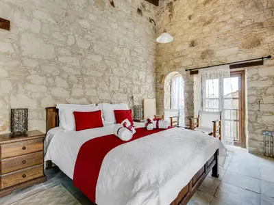 a bedroom with a large bed in a stone wall at Arsorama Village Homes in Arsos