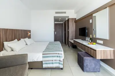 a hotel room with a large bed and a desk at Eleana Hotel in Ayia Napa