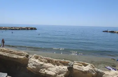 a person standing on a beach near the water at Gulf Palace Apartments in Limassol