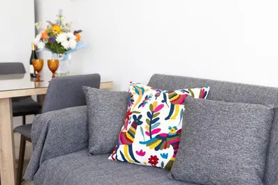 a gray couch with a colorful pillow and a table at Christothea Apartments in Ayia Napa