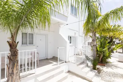 a white building with palm trees in front of it at Christothea Apartments in Ayia Napa