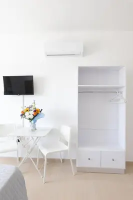 a white living room with a table with a vase of flowers at Christothea Apartments in Ayia Napa