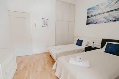 two beds in a room with white walls and wooden floors at Pirgos beach house in Larnaka