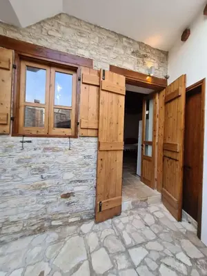 a large room with wooden doors and windows at Christiana's stone studios in Pano Lefkara