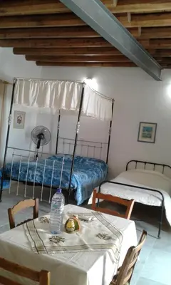 a room with two beds and a table and chairs at Christiana's stone studios in Pano Lefkara