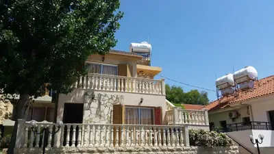 a house with a white fence and a balcony at Kotzias Beach Apartments in Pissouri