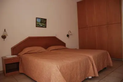 a bedroom with a large bed and a cabinet at Kotzias Beach Apartments in Pissouri