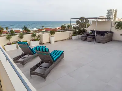 a patio with two chairs and the ocean in the background at The Coral Penthouse in Larnaka