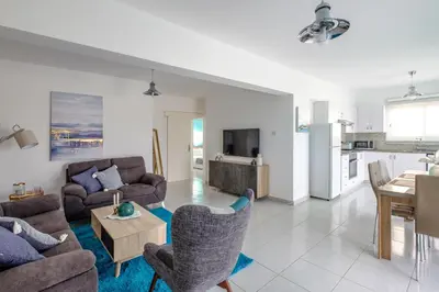 a living room with couches and a table and a kitchen at The Coral Penthouse in Larnaka