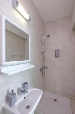 a white bathroom with a sink and a mirror at The Coral Penthouse in Larnaka