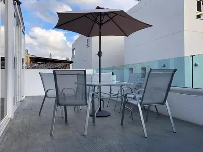 a table and chairs with an umbrella on a balcony at Ayia Napa GO SEA Sunny Apt with Terrace 5 min to Beach in Ayia Napa