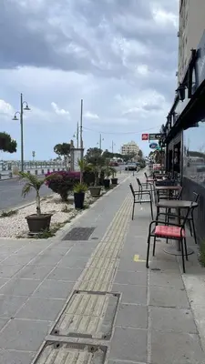 a row of benches on a sidewalk near a street at Stelia's Seagate Studio Apt. in Larnaka