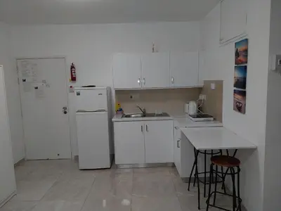 a white kitchen with a sink and a refrigerator at Stelia's Seagate Studio Apt. in Larnaka