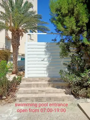 a white building with palm trees and stairs in front at Stelia's Seagate Studio Apt. in Larnaka