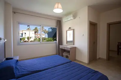 a bedroom with a blue bed and a window at Makronisos Village in Ayia Napa