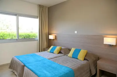 a bedroom with a bed with blue and yellow pillows at Makronisos Village in Ayia Napa