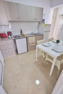 a small kitchen with a white table and chairs at FIG TREE GIANNIS in Protaras