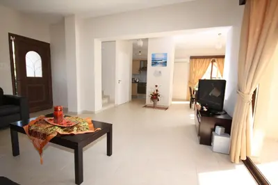 a living room with a table and a tv at Holidays Villas in Pissouri