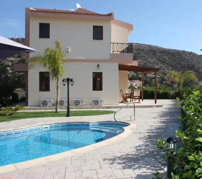 a villa with a swimming pool in front of a house at Holidays Villas in Pissouri