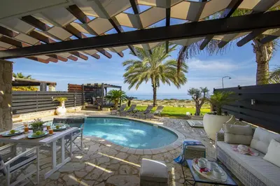 a patio with a pool and a table and chairs at Protaras El Greco Seafront Villa, Greco Mare in Protaras