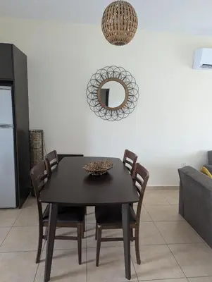 a dining room table with chairs and a mirror on the wall at Kapparis Apartment Mythical Sands in Protaras