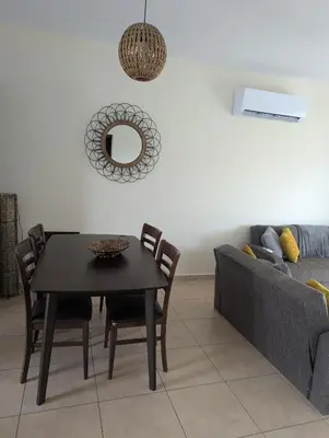 a dining room with a table and a couch at Kapparis Apartment Mythical Sands in Protaras
