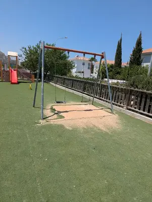 a playground with a swing set in the grass at Kapparis Apartment Mythical Sands in Protaras