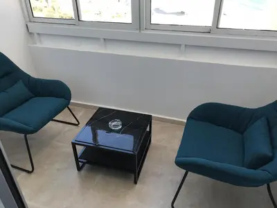 two chairs and a coffee table in a room with windows at Sea View Holiday Apartment in Larnaka
